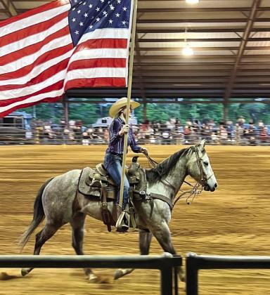 A rodeo performer carries the American flag during the presentation of flags. (CONTRIBUTED)